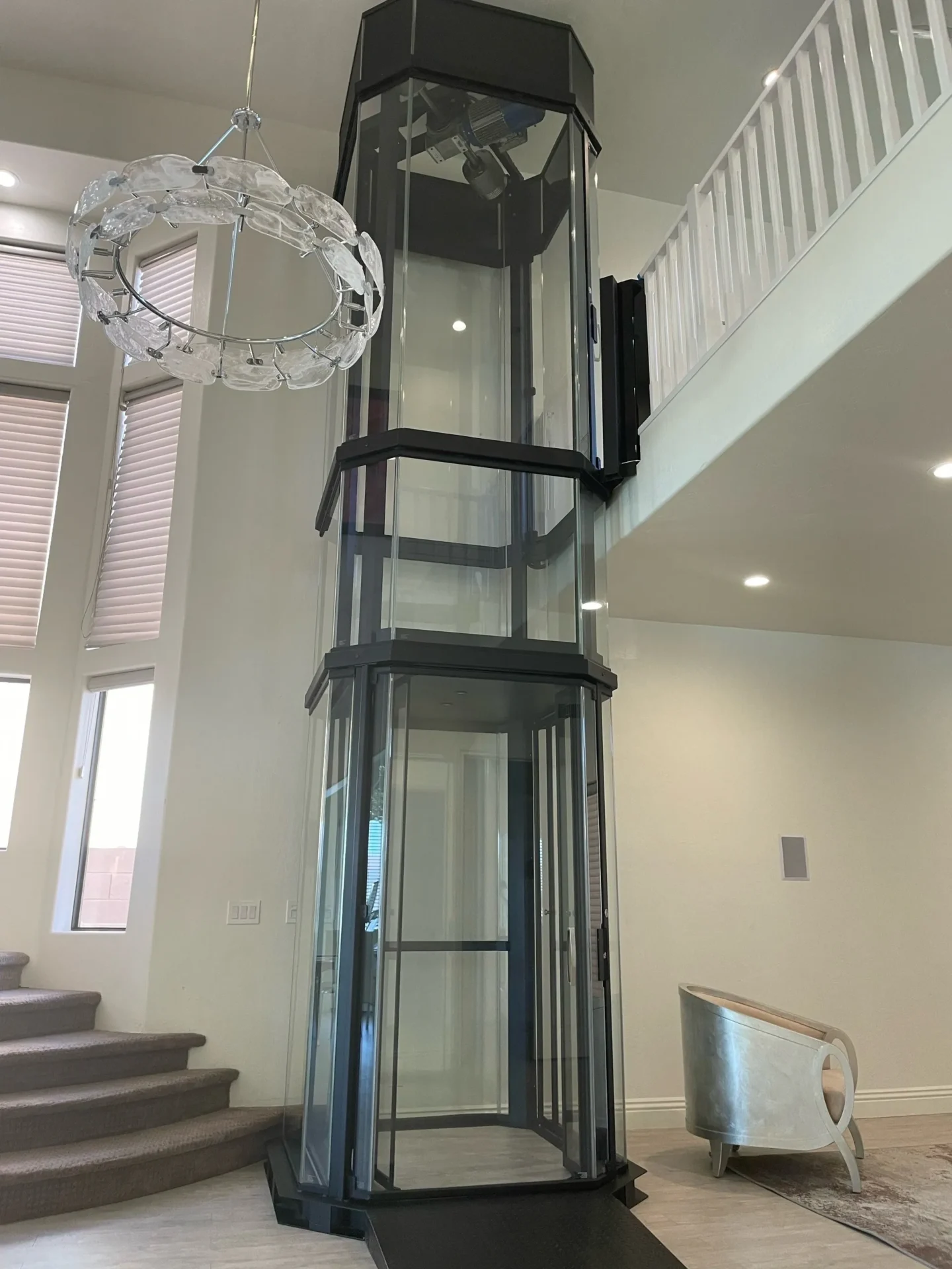 Tall glass home elevator beside staircase